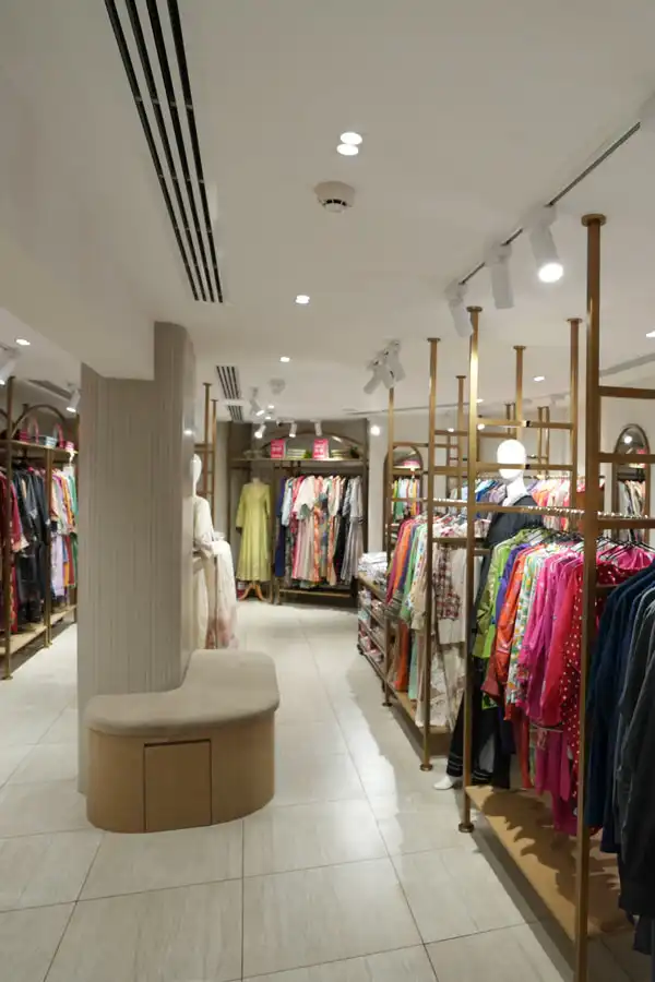Fashion retail store with central aisle seating and elegant display arrangement by Blueprint Experts.