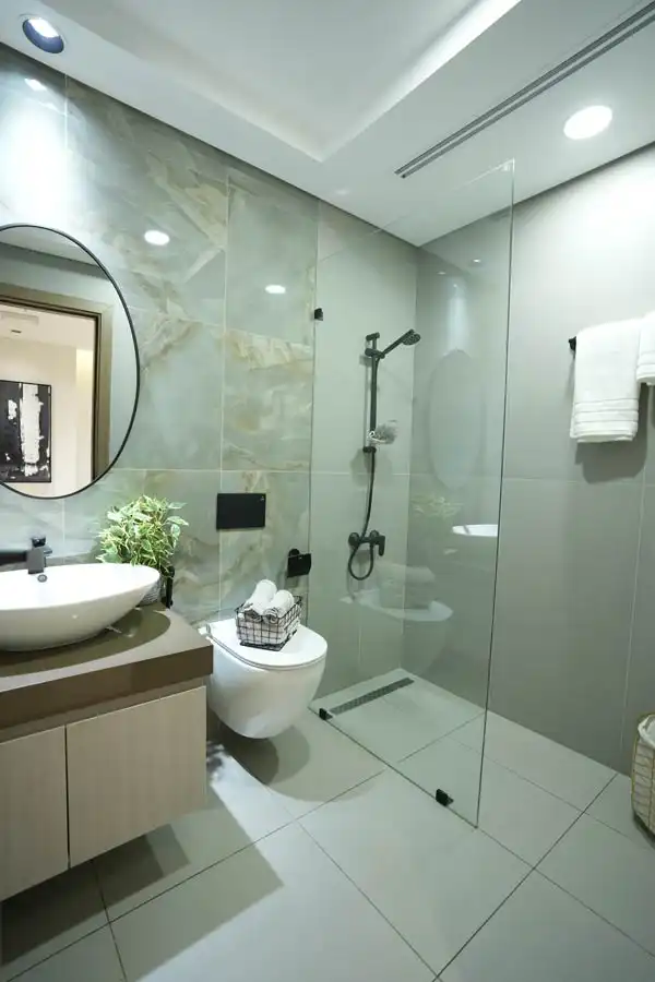 Modern glass shower bathroom with wall-mounted toilet and round mirror