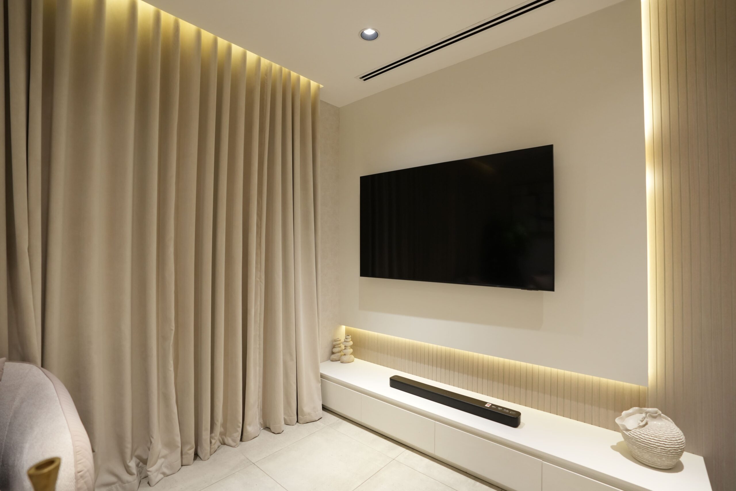 Interior fit out for minimalist living room with custom TV wall unit, soft drapery and integrated LED lighting