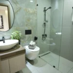 Contemporary bathroom interior fit out with round mirror, designer sink, glass shower cabin, and premium finishes by Blueprint Experts in Dubai.