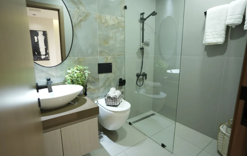 Contemporary bathroom interior fit out with round mirror, designer sink, glass shower cabin, and premium finishes by Blueprint Experts in Dubai.