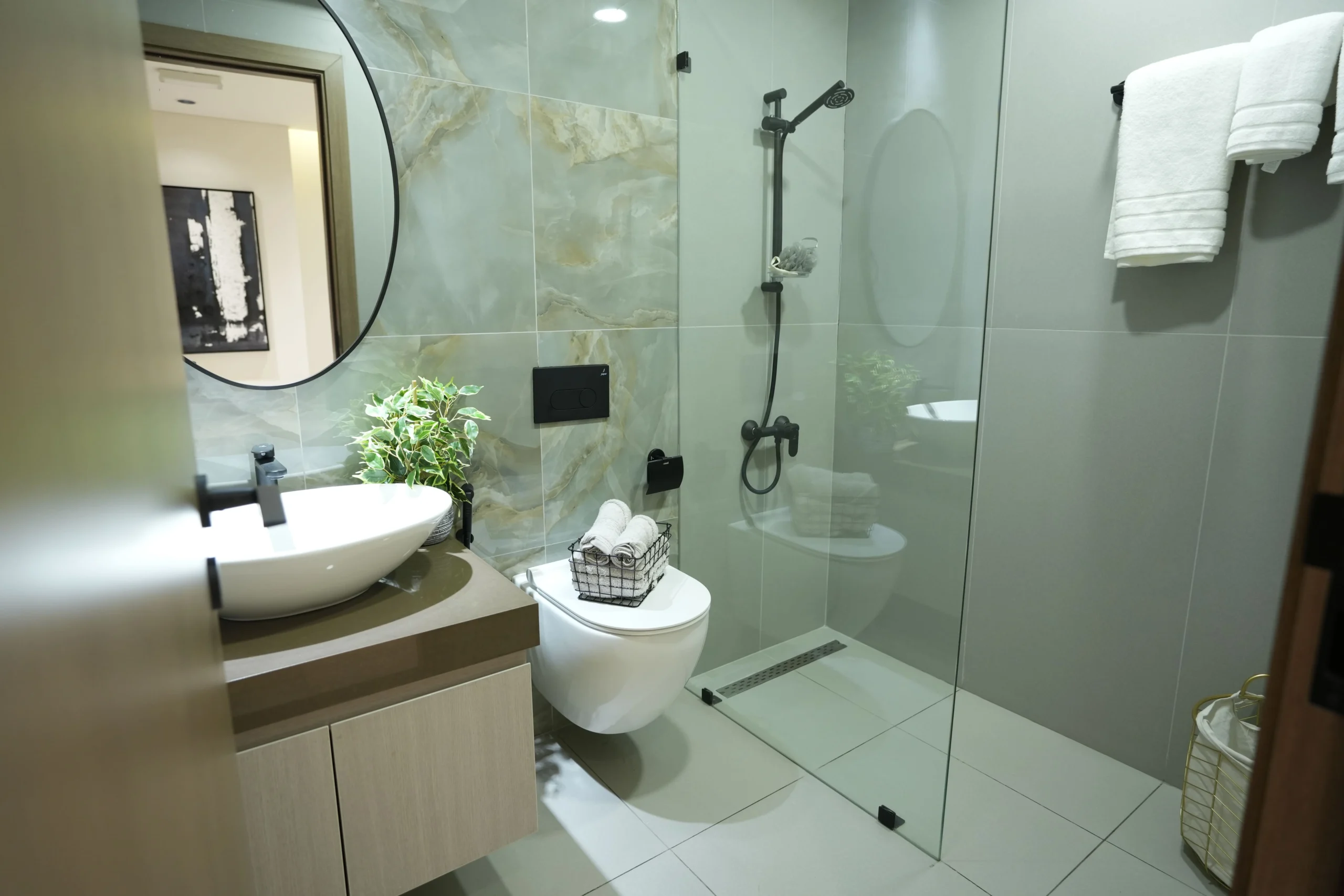 Contemporary bathroom interior fit out with round mirror, designer sink, glass shower cabin, and premium finishes by Blueprint Experts in Dubai.