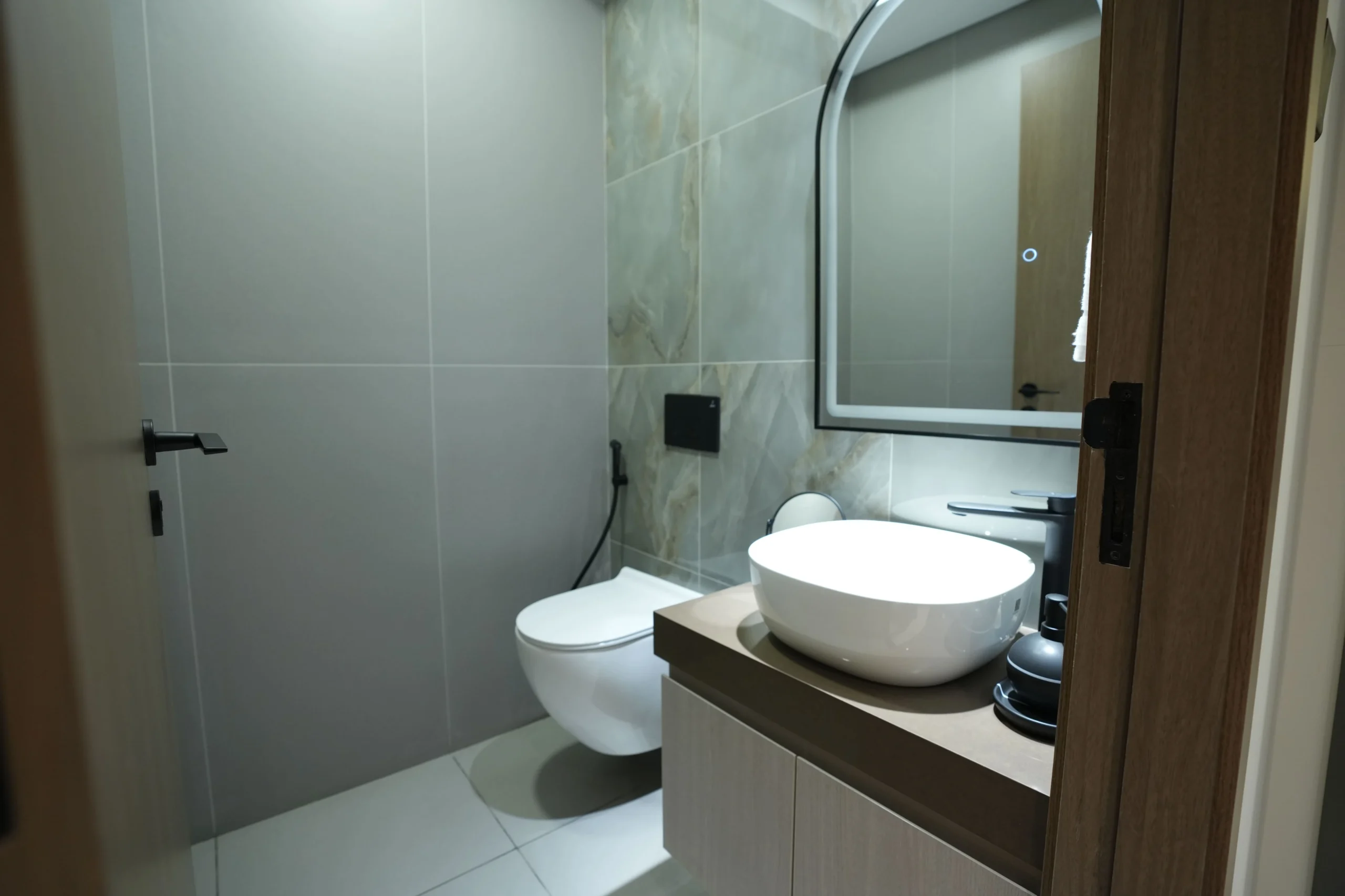 Modern bathroom interior fit out with wall-mounted toilet, matte grey tiles, and contemporary vanity design by Blueprint Experts in Dubai.
