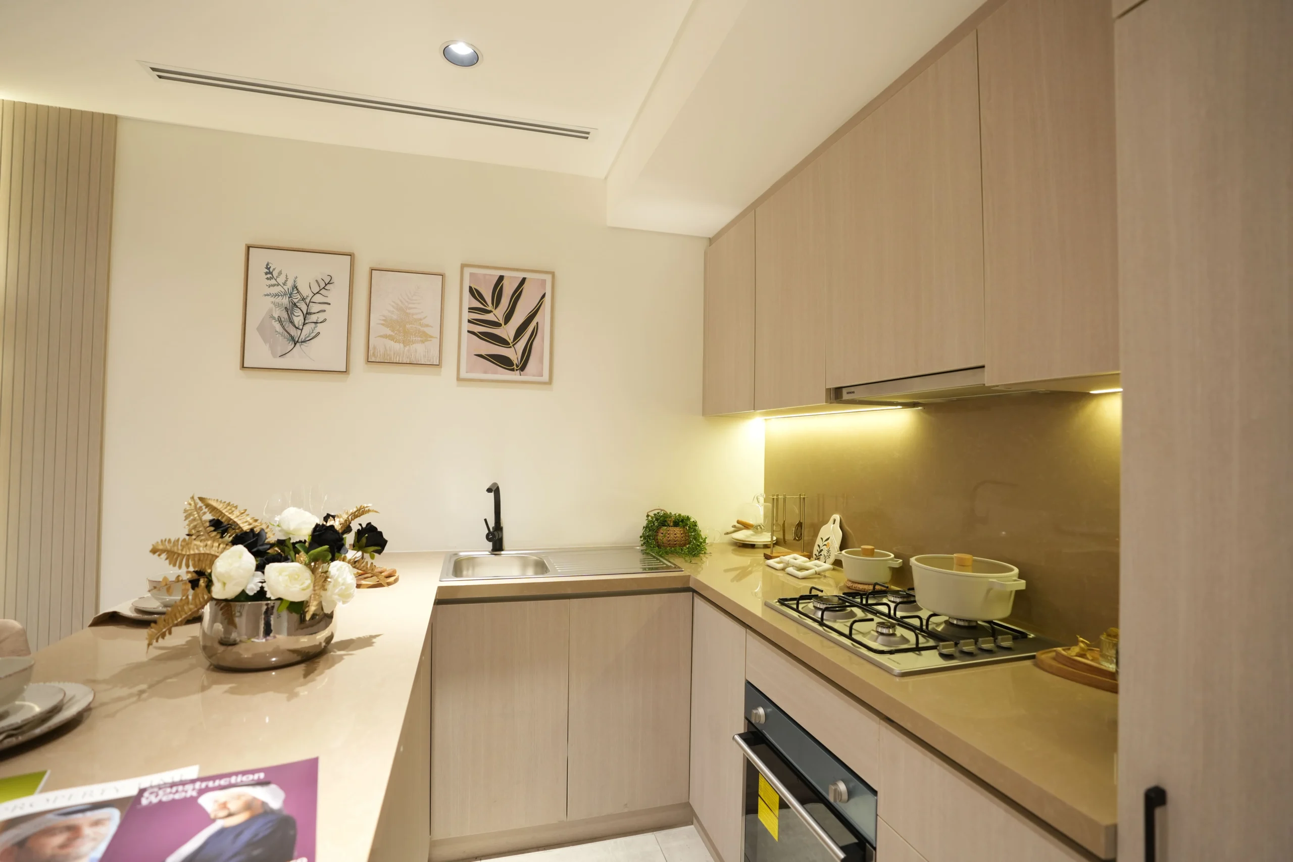 Modern kitchen fit out in Dubai with light wood cabinets, integrated appliances, and warm under-cabinet lighting by Blueprint Experts.