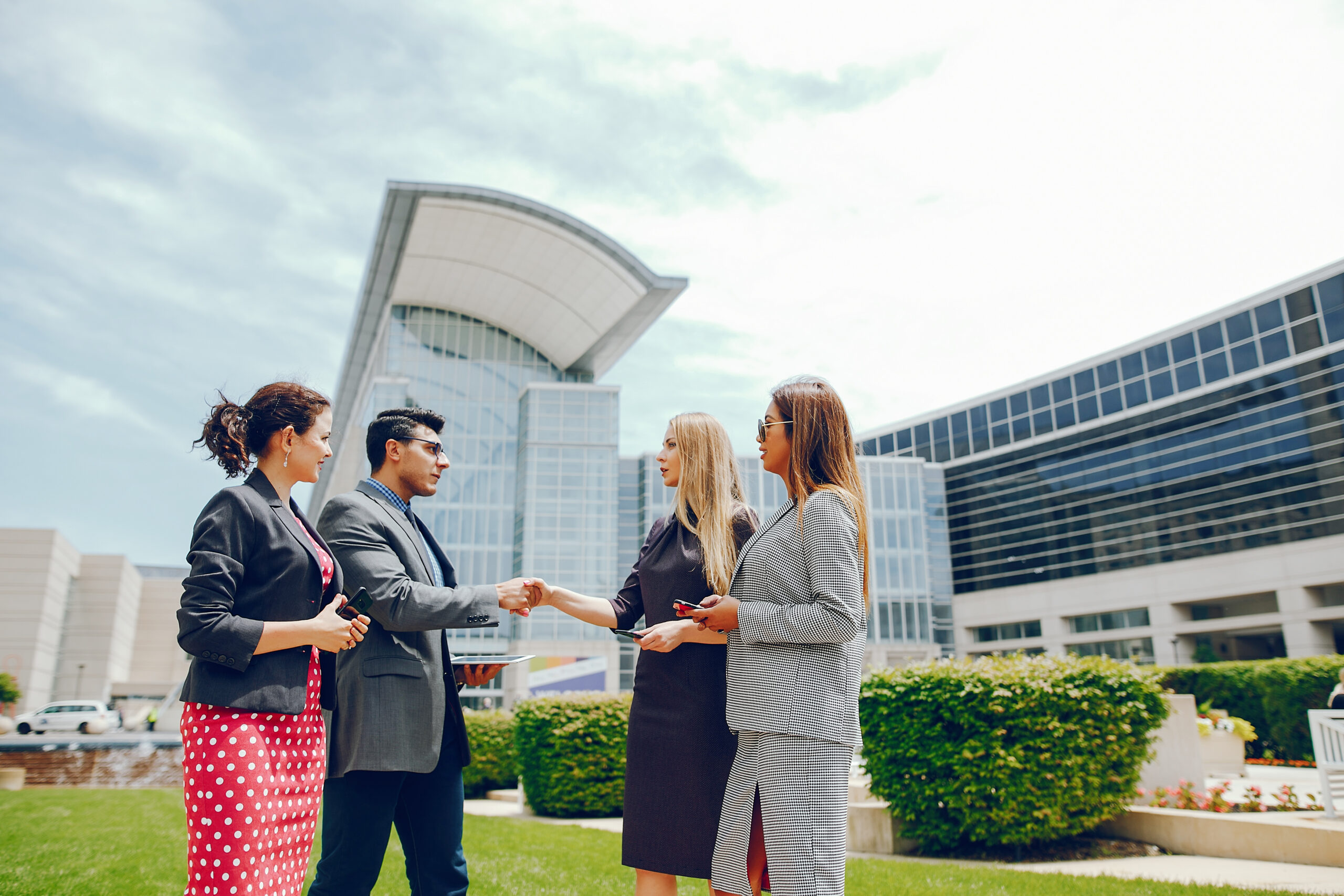 Handsome businessman in a city. Businessman in a glasses. Business partners in a summer city. Man and three women standingin a sity with tablet and phones